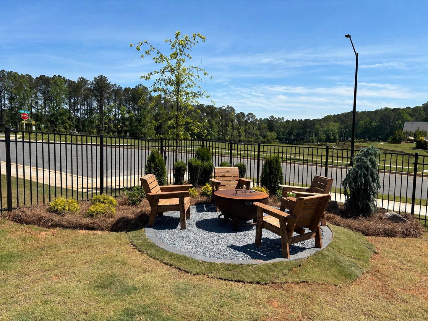 Ground-level view of a circular gravel fire-pit patio with wood seating