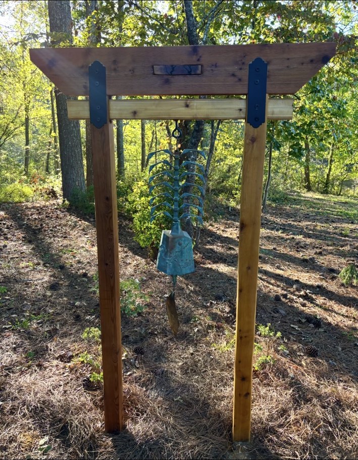 Timber frame supporting a sculptural hanging garden bell