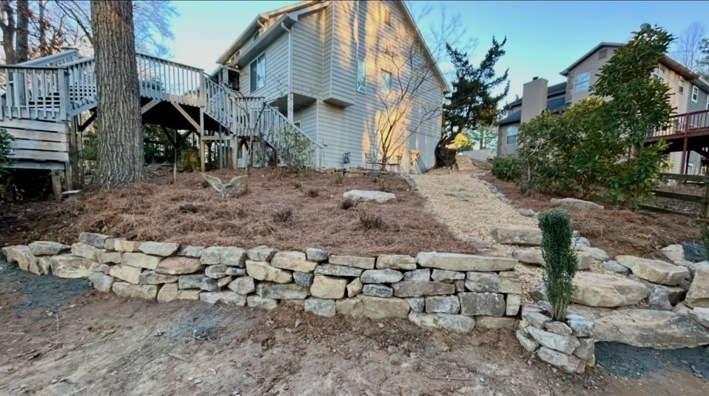 Natural stone wall bordering a sloped side yard